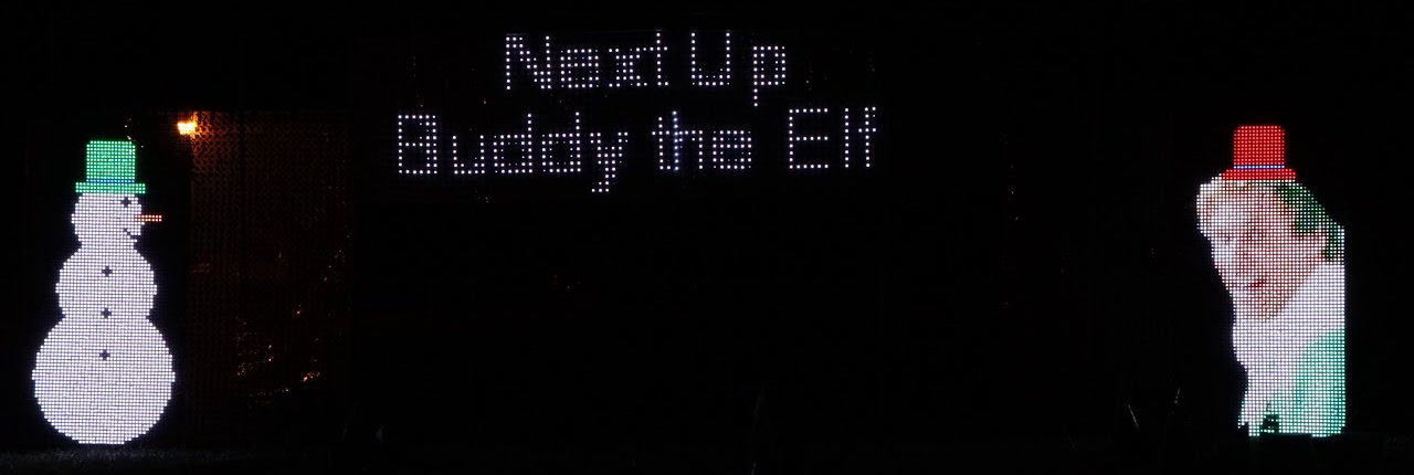 The two pixel snowmen with "Next Up Buddy the Elf" on the grid between them, and the right snowman turned into Buddy the Elf